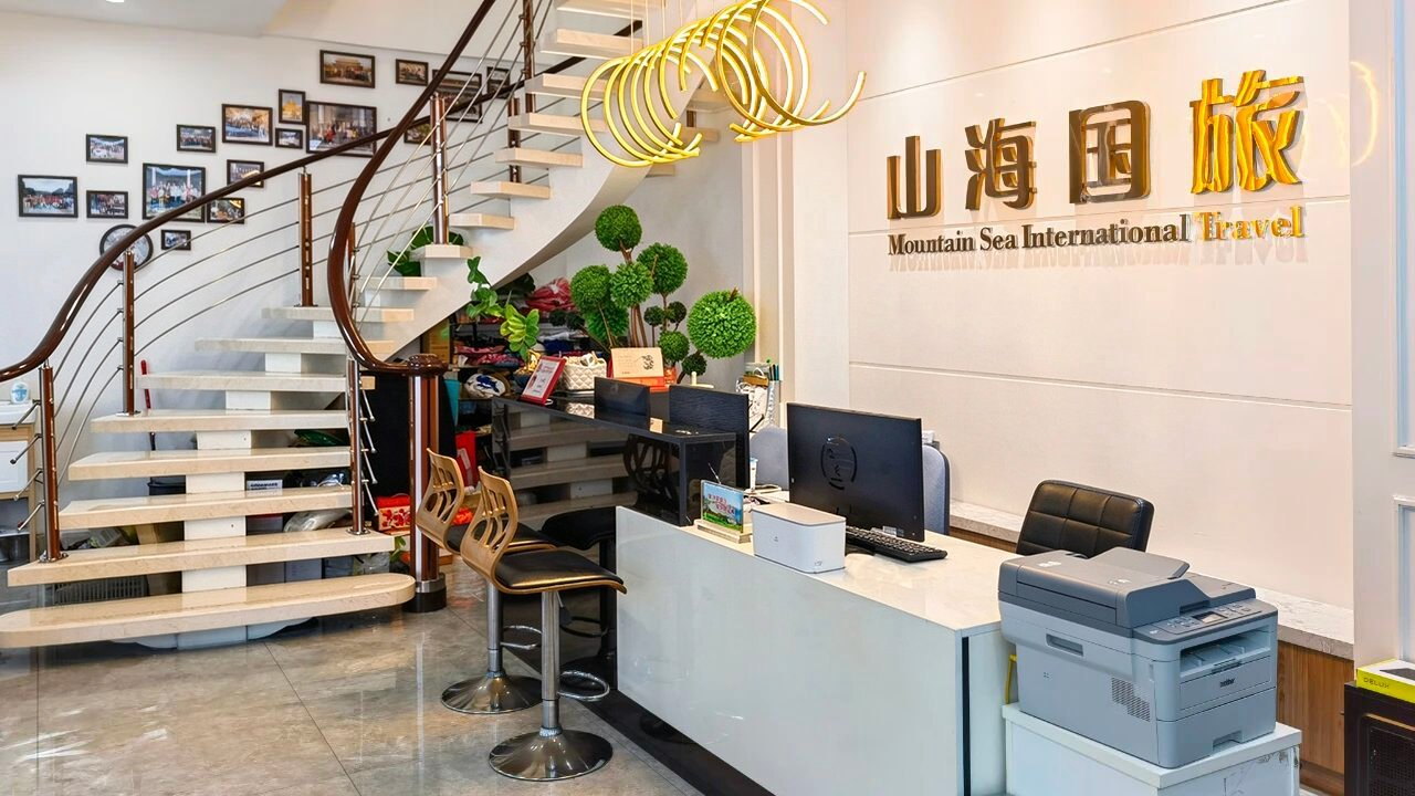 汕头市山海国际旅行社前台接待区，金色山海国旅立体字形象墙、旋转楼梯与螺旋吊灯